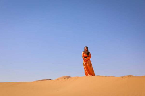 Beautiful young girl in Moroccan dress in Sahara desert.