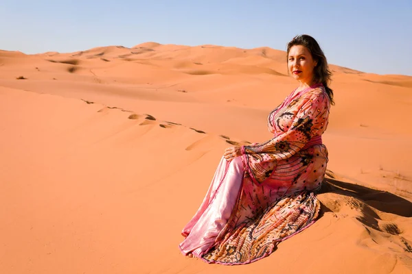 Girl in Moroccan dress in Sahara desert.