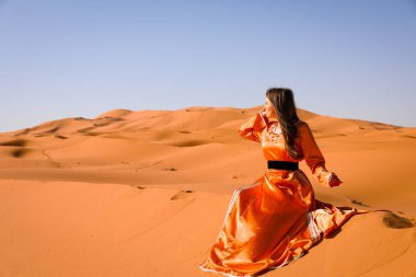 Beautiful young girl in Moroccan dress in Sahara desert. clipart