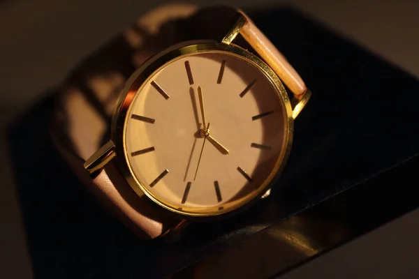 It will be three o\' clock. Golden color watch on top of the box