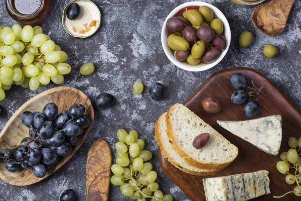 snacks of blue cheese, olives, bread and grapes