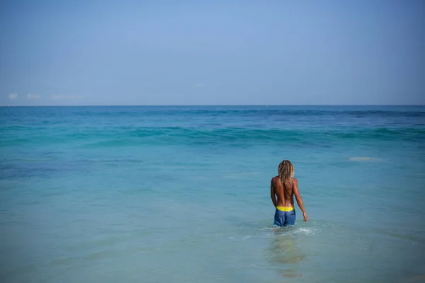 Panoramic portrait of an attractive curly wet man is going into the ocean and. View from back — Stock Photo, Image