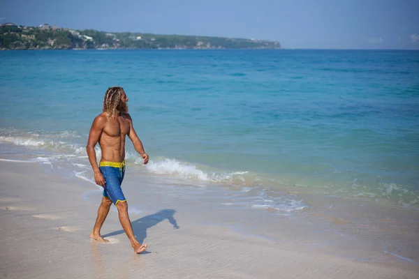 Attraktiver muskulöser bärtiger blonder Lockenkopf mit nacktem Oberkörper spaziert am Strand — Stockfoto