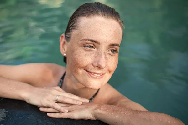 Retrato horizontal de cerca de una hermosa chica con manchas solares y cabello mojado en el agua, brazos en el borde de la piscina —  Fotos de Stock