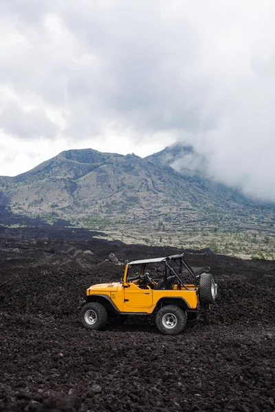 Offroad yelow vehicle parked at the top of a valley with volcanic rock and mountains in Bali, Indonesia — Stock Photo, Image