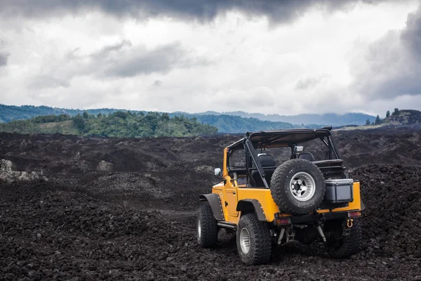 A hátsó nézet sárga offroad jármű parkolt egy völgyben, a vulkanikus kőzet és Bali, Indonézia-hegység tetején — Stock Fotó
