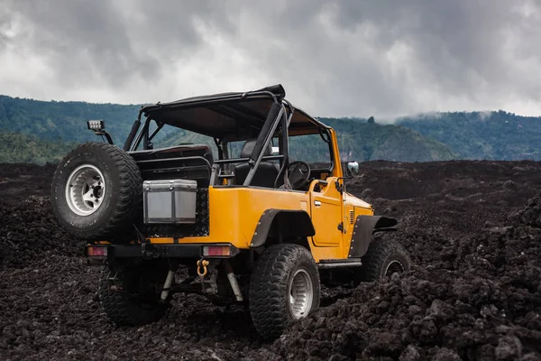 A hátsó nézet sárga offroad jármű parkolt egy völgyben, a vulkanikus kőzet és Bali, Indonézia-hegység tetején — Stock Fotó