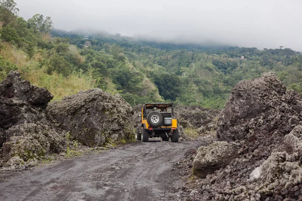 Sárga offroad jármű hátsó nézet hajtott egy vezető úton egy sötét föld. — Stock Fotó