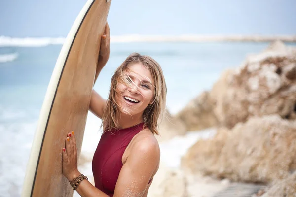 Horizontální detail portrét dívky atraktivní šťastné surfování v tmavě červená plavky drží surfu na pláži a při pohledu do kamery — Stock fotografie