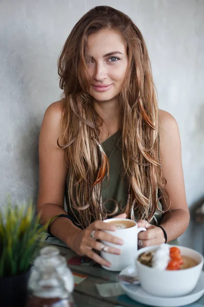 Vacker flicka med kopp kaffe och musli skål sitter på ett café — Stockfoto