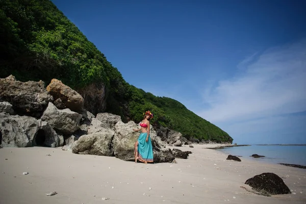 Hermosa chica con corona de flores en el pelo está de pie en una playa — Foto de Stock