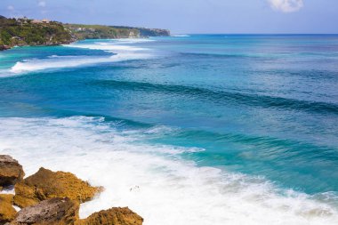 Parlak mavi okyanus beyaz köpük dalgalar ve sahil uzaktan