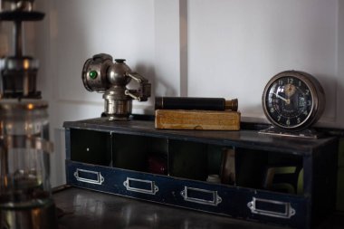 Yirminci yüzyılın modası geçmiş eski nesneleri masada. Klasik çalar saat, dürbün, eski cam pompa.