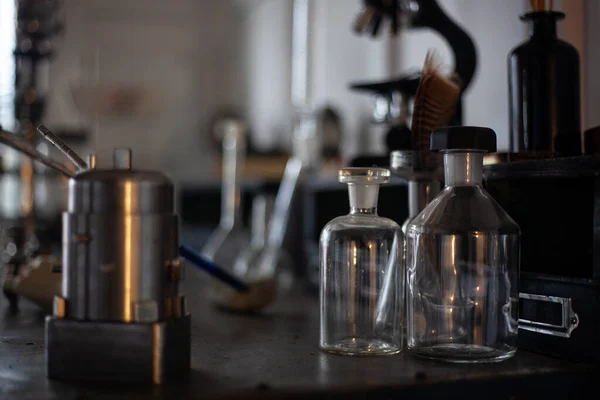 Staromodne obiekty retro XX wieku na stole. Vintage szklane butelki, stare szklane kolby, mikroskop na tle — Zdjęcie stockowe