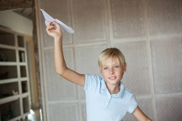 Mavi tişörtlü yakışıklı sarışın adam elinde kağıt bir uçak tutuyor ve onu uçuracak.