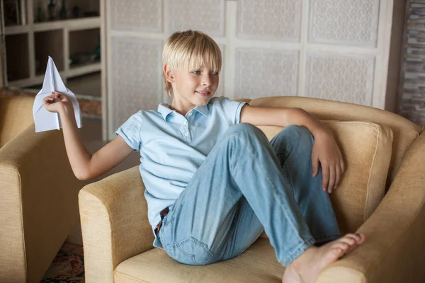 Mavi tişörtlü yakışıklı sarışın genç adam koltuğuna oturur ve elinde bir kağıt uçak tutar ve onu uçurur. Eğleniyorum.