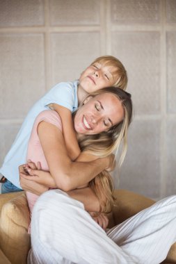 Genç ve güzel annenin ve küçük oğlunun kucaklaşmaları. Mutlu sarışın aile.