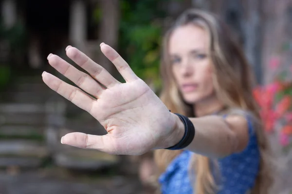 attractive blond girl outdoor doing stop sing with palm of hand. Warning expression with negative and serious gesture on face. focus on hand. stay at home, keep distance, isolation