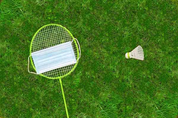 Símbolo Protección Contra Coronavirus Raqueta Bádminton Lanzadera Sobre Hierba Verde —  Fotos de Stock