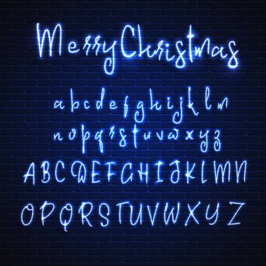 Latince neon yazı tipi mutlu Noeller. Parlayan alfabesi, elektrik standı, bir tuğla duvar arka plan, kaligrafi Abc..