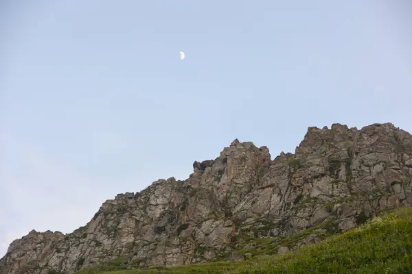 Rocky contra el cielo azul y hermosa media luna en la noche —  Fotos de Stock