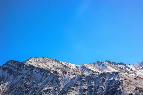 Зимний снег покрыл горные вершины над голубым небом. Кыргызстан . — стоковое фото