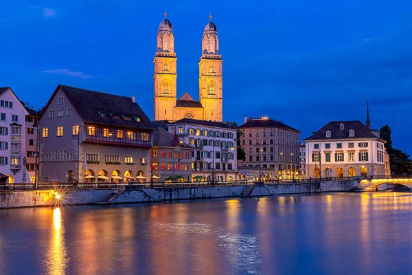 Zurich. Vista del terraplén de la ciudad y la iglesia Grossmunster al atardecer . — Foto de Stock