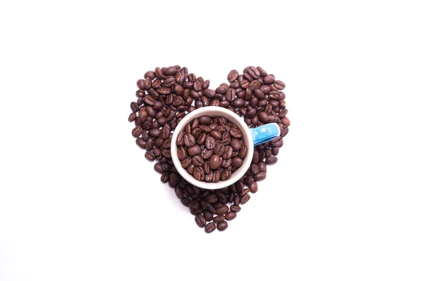 Forma de corazón creado con granos de café y una taza — Foto de Stock