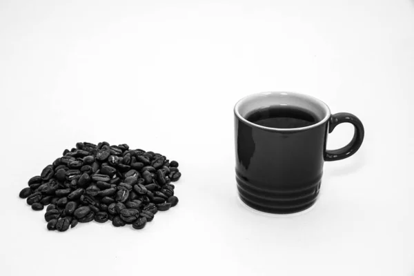 Czarno-biały kubek kawy przez stos ziaren kawy — Zdjęcie stockowe