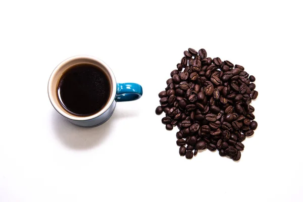 Niebieska filiżanka kawy przez stos ziaren kawy — Zdjęcie stockowe