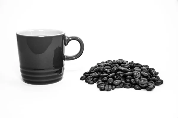 Tasse de café noir et blanc par une pile de grains de café — Photo