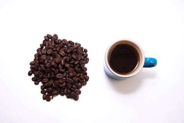 Xícara azul de café por uma pilha de grãos de café — Fotografia de Stock