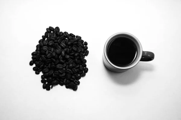 Черно-белая чашка кофе у кучи кофейных зерен — стоковое фото