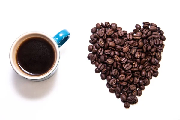 Forma de coração criado com grãos de café e uma caneca — Fotografia de Stock