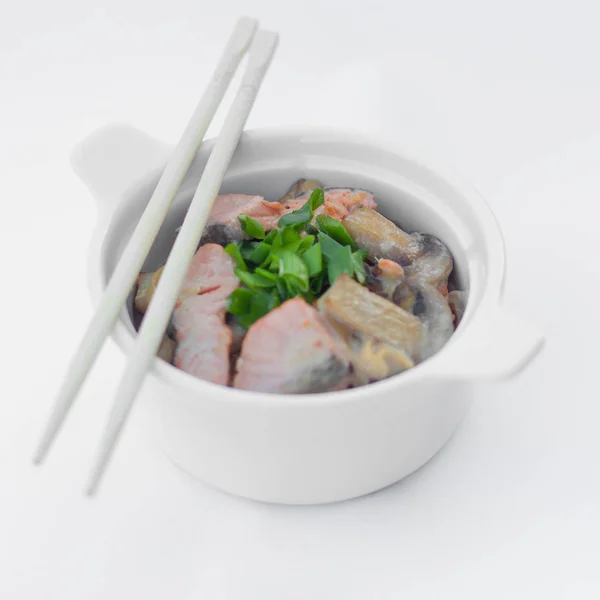 Isolerade kinesisk mat på en vit bakgrund. Mat är placerad i potten. I närheten ligger ätpinnar. — Stockfoto
