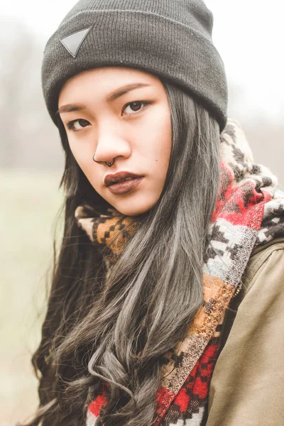 Hermosa mujer de aspecto asiático drama mira a la cámara en un campo de fondo. Primer plano de la imagen / plano medio . — Foto de Stock