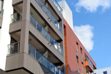 Modern bir konut mimarisi örneği - blu gökyüzü arka planında balkonları ve pencereleri olan bir binanın dış kısmı