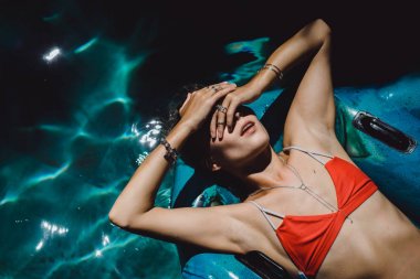 Kadın kırmızı bikini şişme yuvarlağına yalan