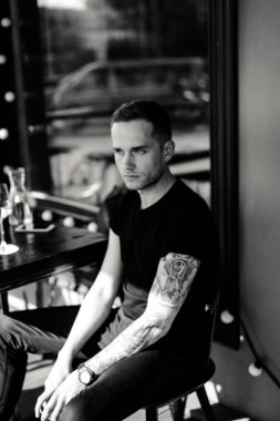 yaz terasında oturan dövmeli adam