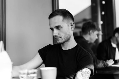 yaz terasında oturan dövmeli adam