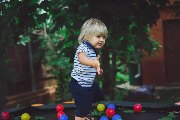 Menino pulando no trampolim com bolas coloridas — Fotografia de Stock