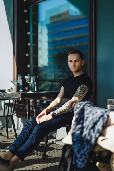 Tätowierter Mann sitzt auf Sommerterrasse — Stockfoto