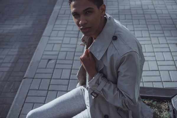 man in coat posing in street cafe