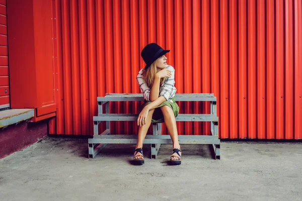 Mädchen mit Hut sitzt auf Holztreppe — Stockfoto