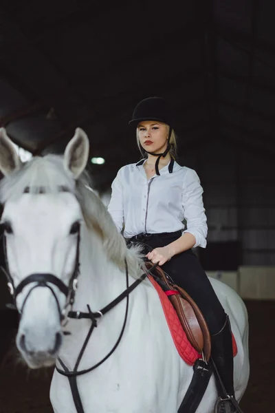 girl in outfit sitting on horse in arena