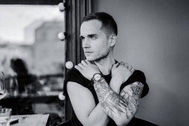 yaz terasında oturan dövmeli adam