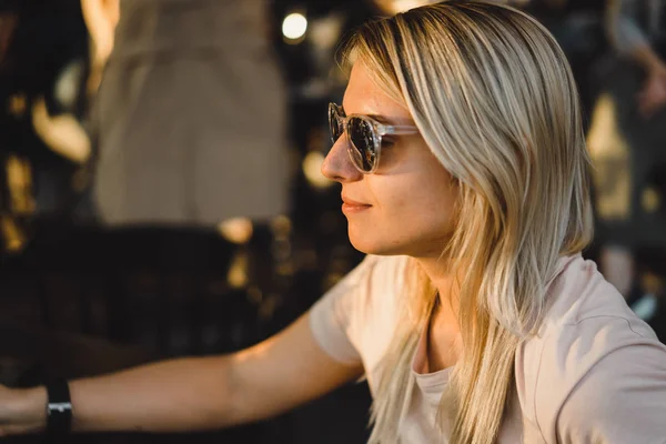 Blond žena v sluneční brýle ve venkovní kavárně — Stock fotografie
