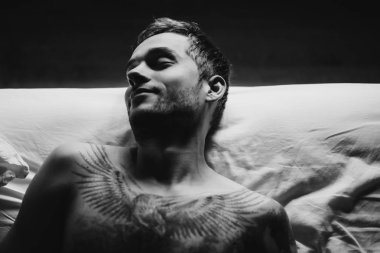 dövmeli adam yatakta uyuyor