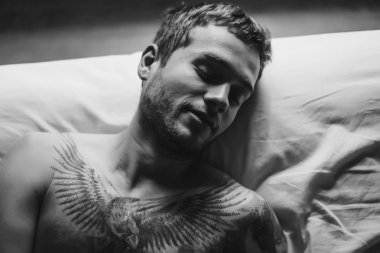 dövmeli adam yatakta uyuyor