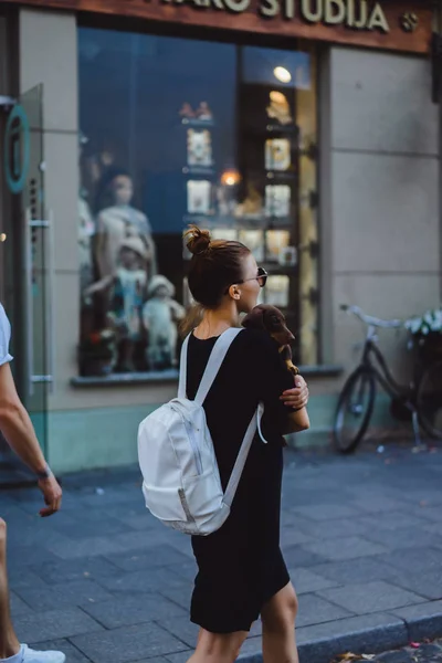 Vrouw lopen met rugzak en hond in handen — Stockfoto
